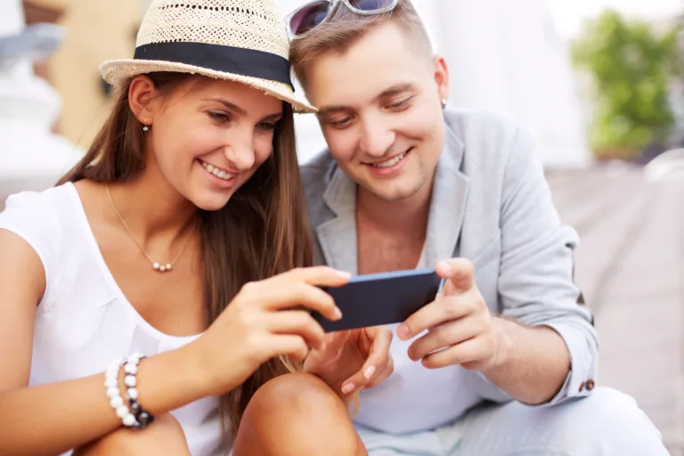 Mlad par, ki na mobilnem telefonu upravlja nastavitve v mobilni banki.